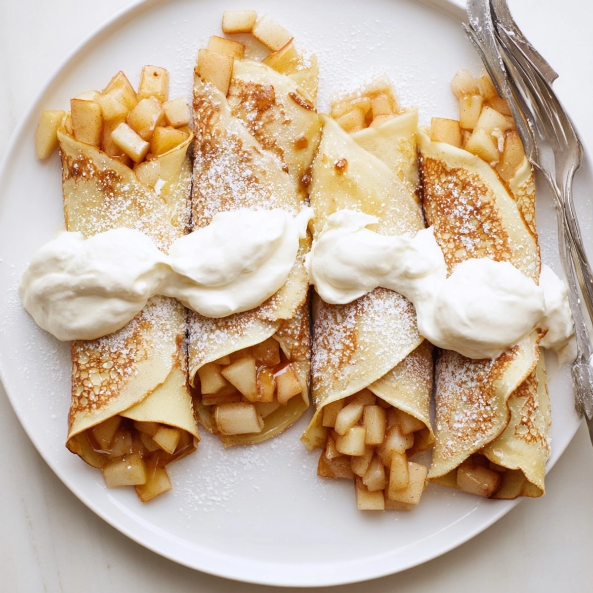 Homemade Mini Apple Nalesniki: each sweet crepe is filled with spiced apples and folded.