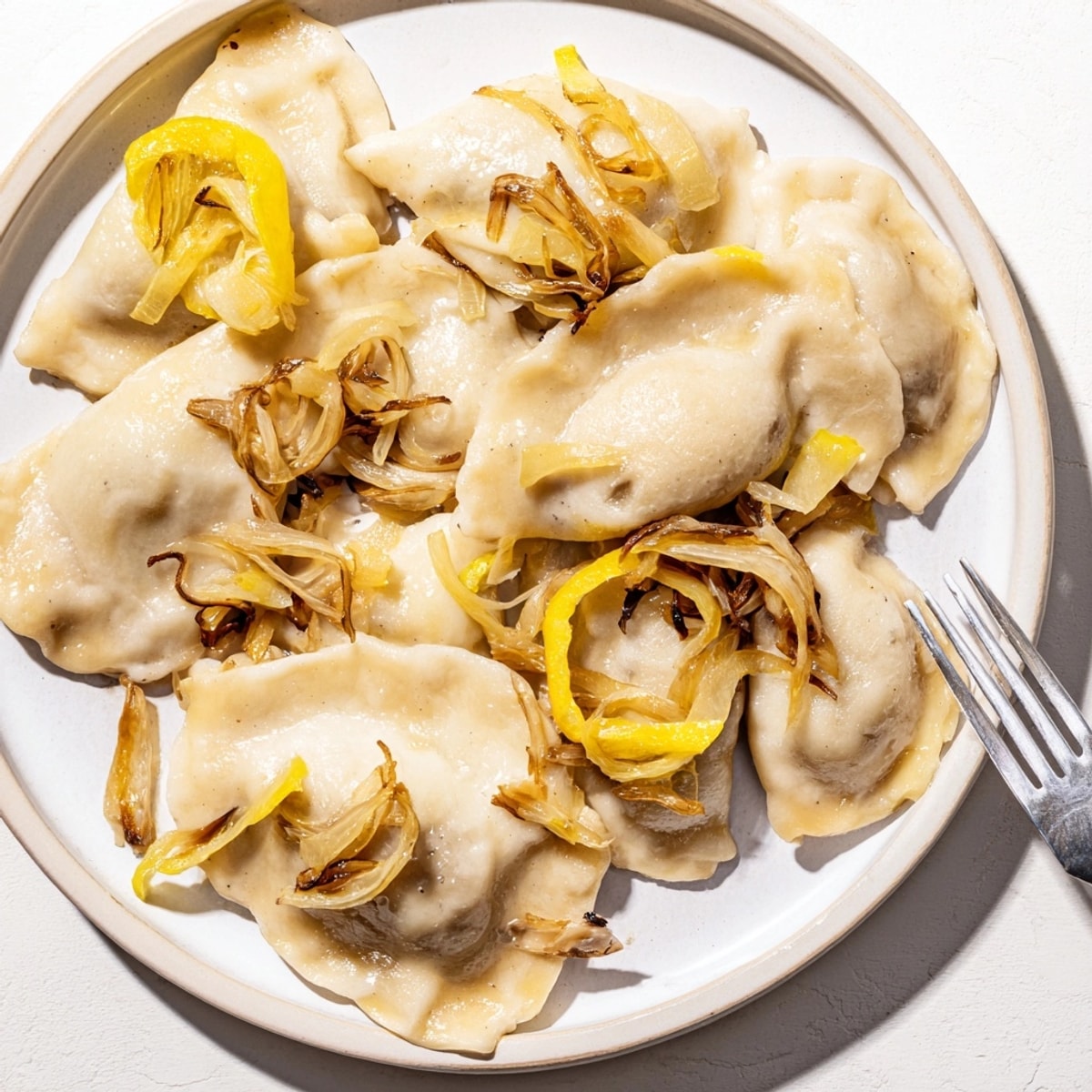 Złociste wegańskie pierogi z kapustą kiszoną zwieńczone słodką karmelizowaną cebulką, ciepłe i sycące danie.