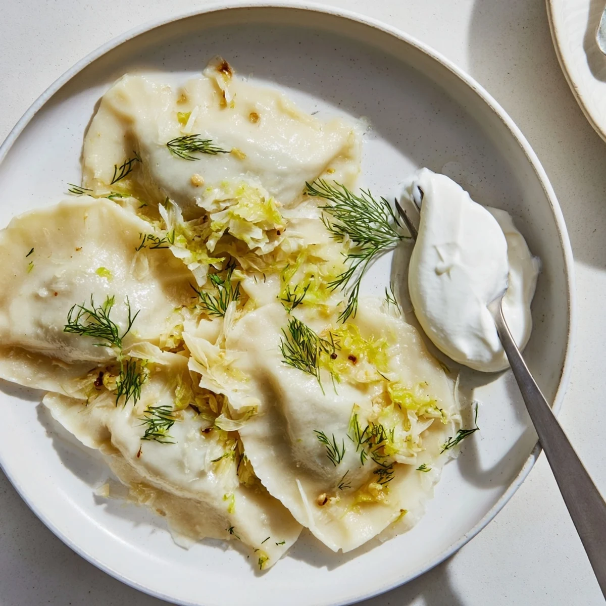 Pierogi z kapustą i grzybami, posypane świeżymi ziołami i roztopionym masłem.