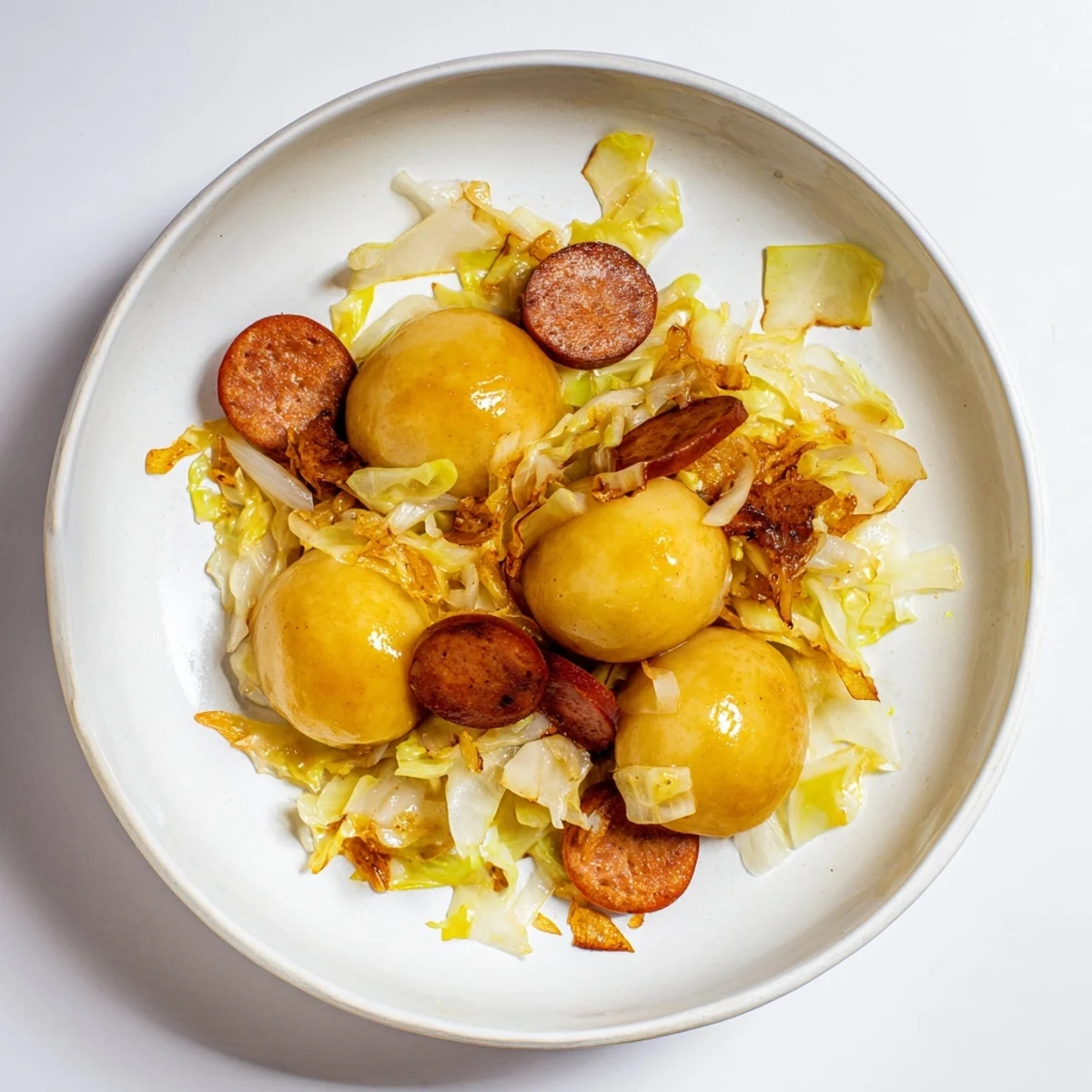 Close-up of perfectly cooked kopytka, with kielbasa and cabbage, ready to enjoy.