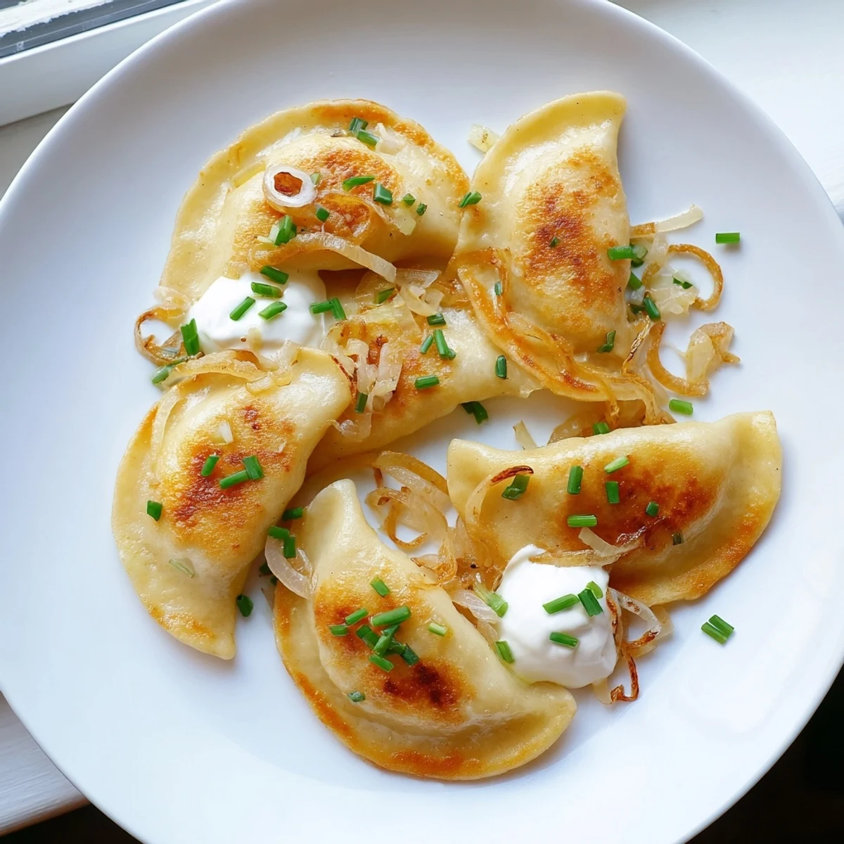 Steaming plate of Authentic Potato and Cheese Pierogi Ruskie, with crispy fried onions, a hearty Polish meal.