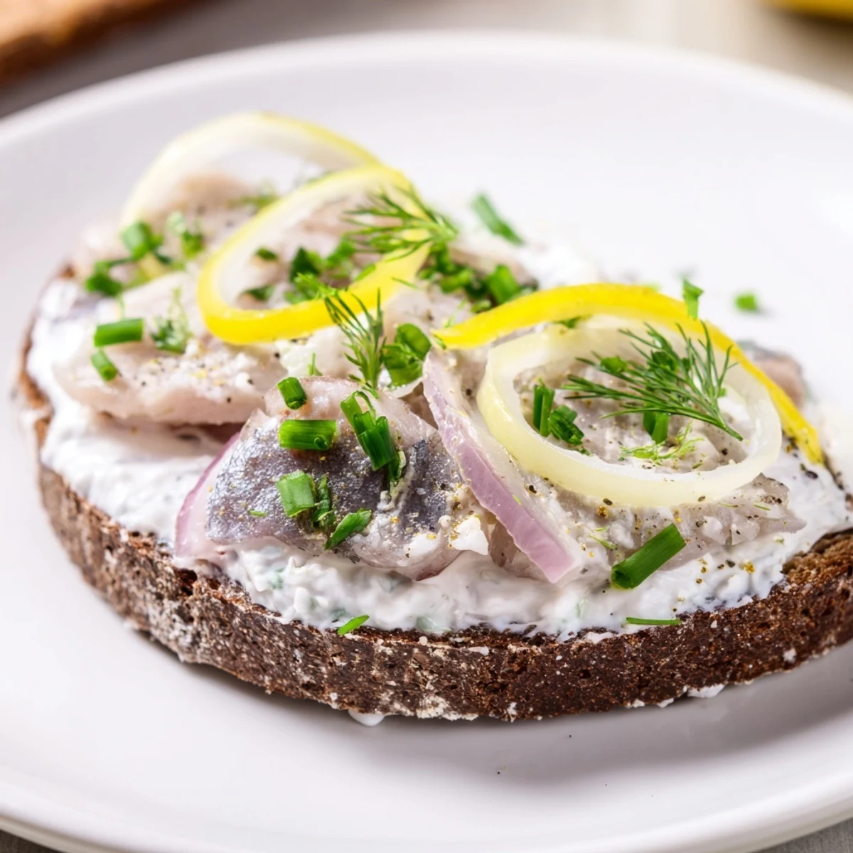 Znakomity śledź! Kremowy ser na pumperniklu, z dodatkiem marynowanego śledzia, zachęca do lunchu.