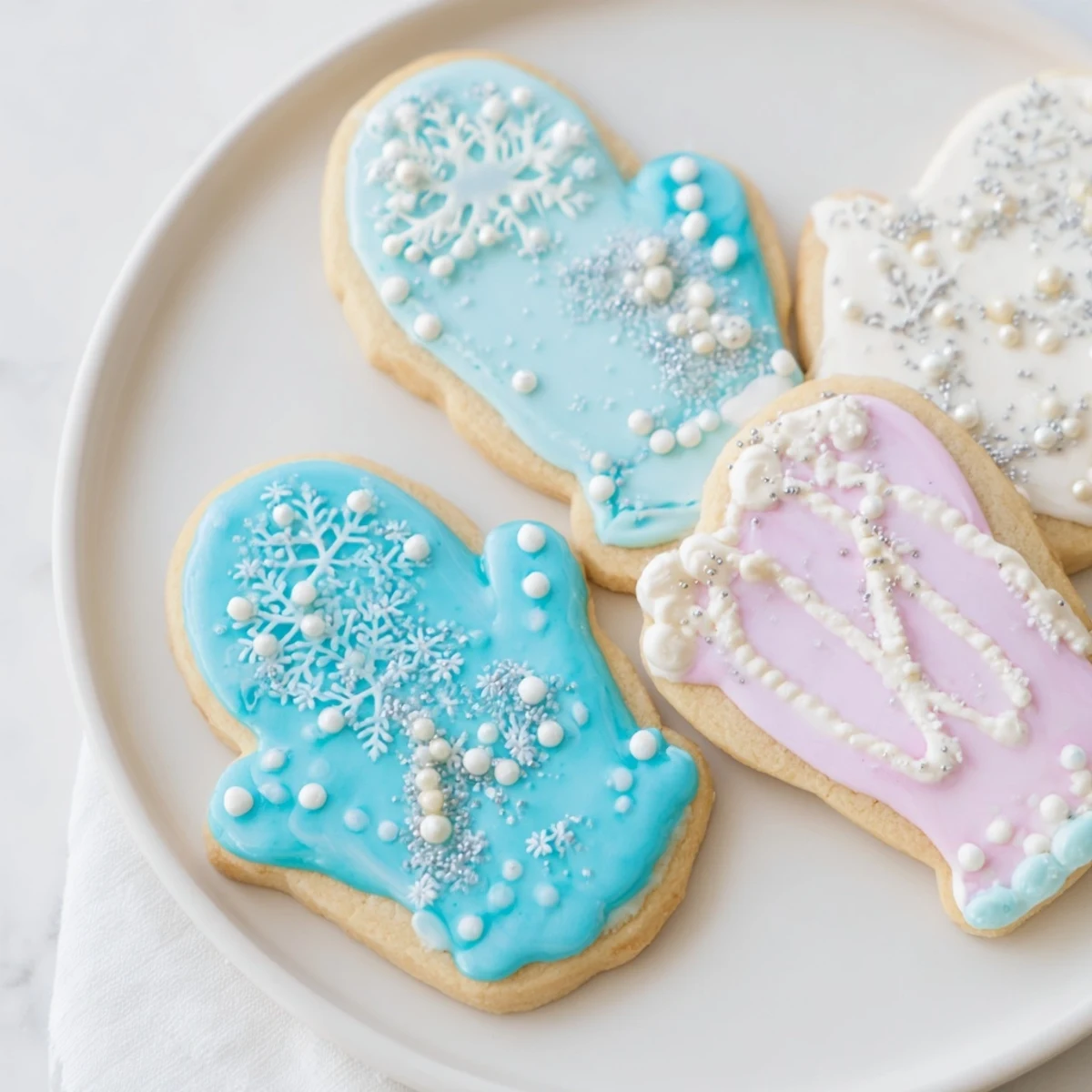 Ciepłe i tosty ciasteczka w kształcie rękawiczek, udekorowane kolorowym lukrem, idealne na zimowe przyjęcia.