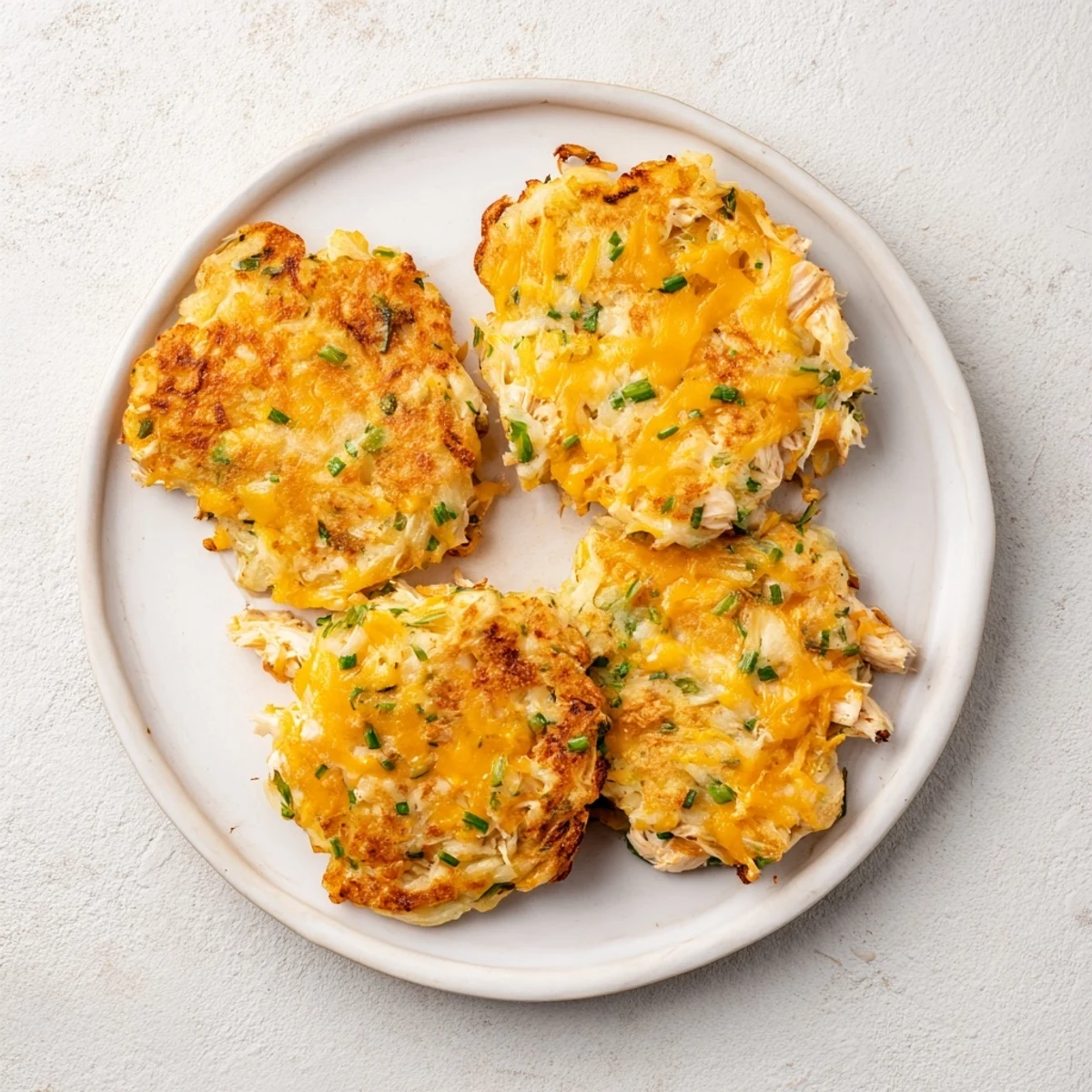 Ułóż ciepłe placuszki z ziemniakami i kurczakiem na talerzu, idealne na szybki lunch.