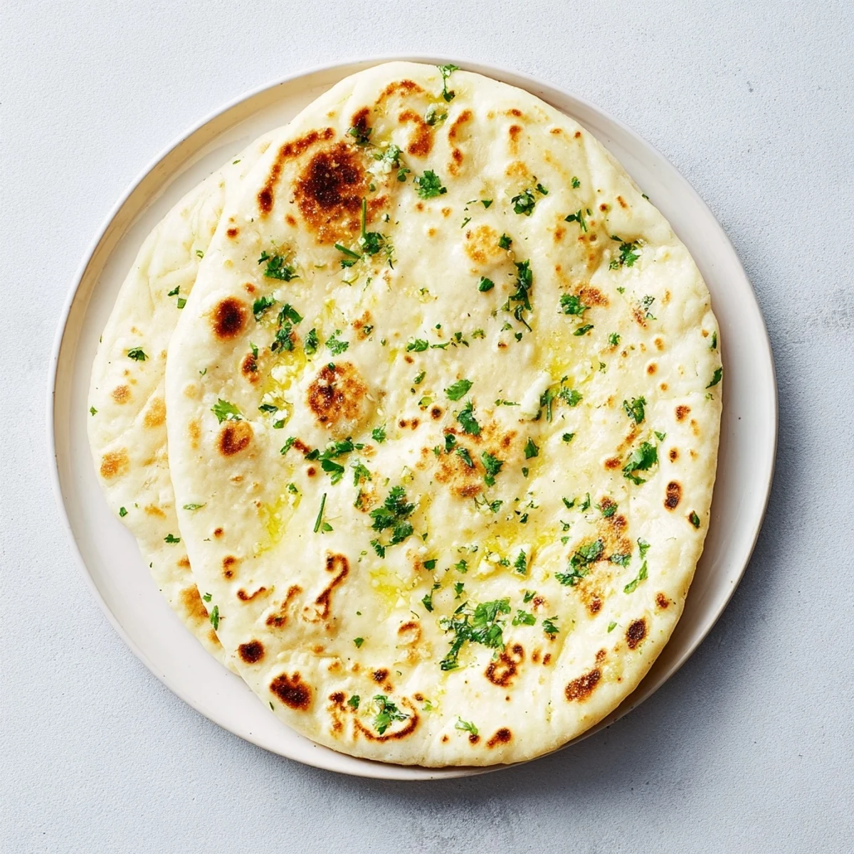Homemade Garlic Naan Bread, golden and bubbly after being cooked in a hot skillet, ready to serve.
