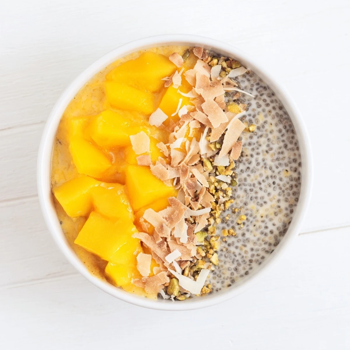 Creamy mango coconut chia pudding dessert, beautifully layered, garnished with fresh mango chunks.
