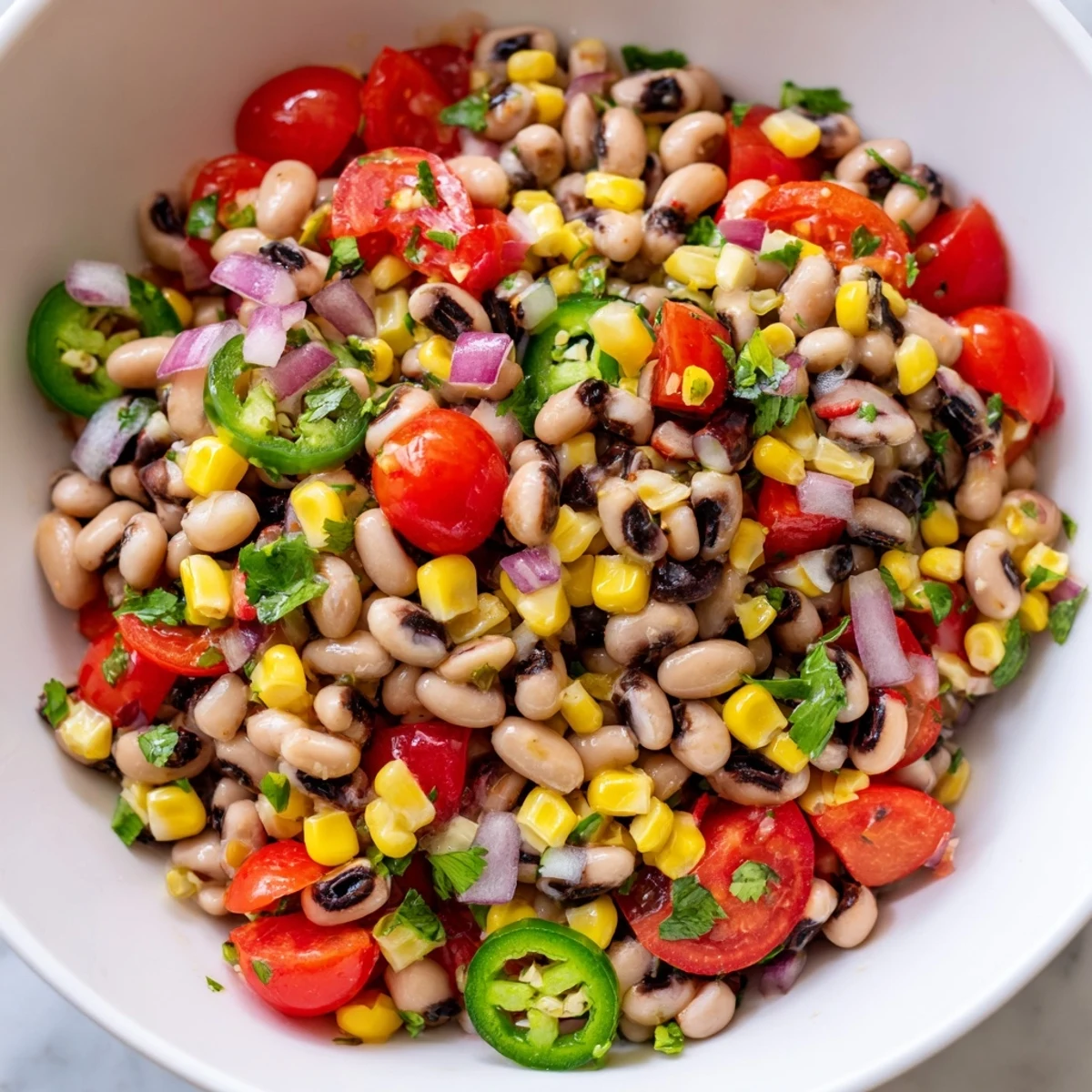 Kolorowa misa cowboy caviar pełna fasoli, kukurydzy i papryki, skropiona cytrynowym dressingiem.