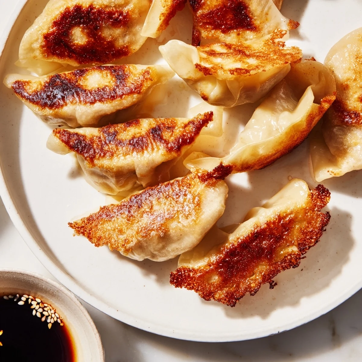 Pan-fried Smashed Gyozas in a skillet, golden brown and crispy on the bottom, served with a side of soy-vinegar dipping sauce.