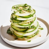 Warstwowa przekąska z jicamy i ogórka, posypana kolendrą i sezamem, gotowa do spożycia.