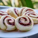 Freshly cut Simple PB&J pinwheel rolls, showcasing the vibrant jam and creamy peanut butter layers.