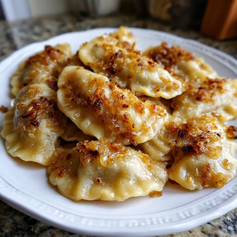 Na tle kantu stoi biały talerz z buckwheat & onion pierogami. Pierogi są na talerzu w dużych ilościach, a ich smak jest wyjątkowy.