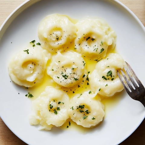 Silesian Dumplings in Butter Sauce: Soft potato pillows glistened with a rich, golden sauce.