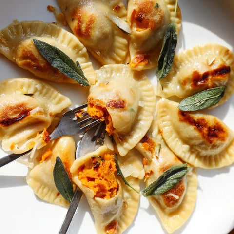 Golden pan-fried pierogi with autumn pumpkin filling, sage butter glistening; comforting, flavorful.