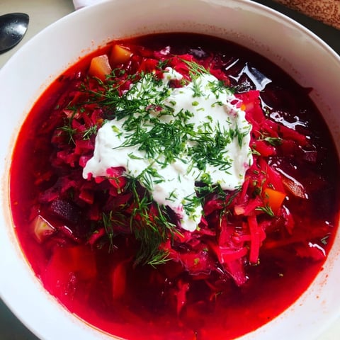 Miseczka ciepłego czerwonego barszczu z mleczkiem kokosowym, posypana świeżym koperkiem, idealna na wegański lunch.