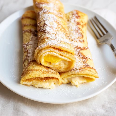 Delikatne blintzes serowe z owocowym kompotem, idealne na śniadanie lub deser.  