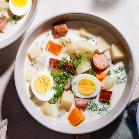 Hearty bowl of Modern Żurek with rye bread, garnished with eggs and fresh dill.