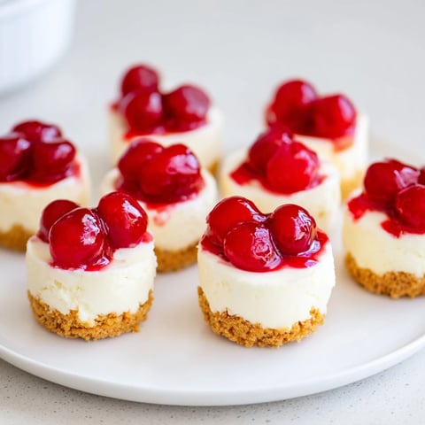 Kruche mini serniczki z wiśniami, z kremowym nadzieniem waniliowym i słodkimi wiśniami.