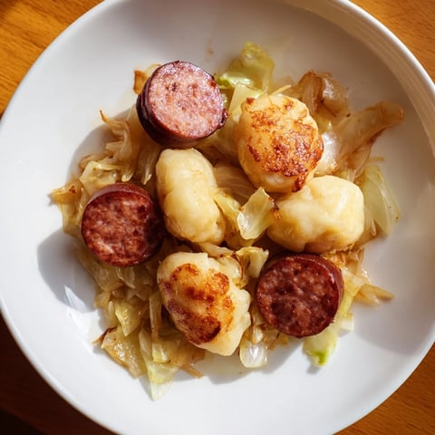 Golden-brown kopytka with kielbasa and cabbage: a hearty Polish comfort food feast.