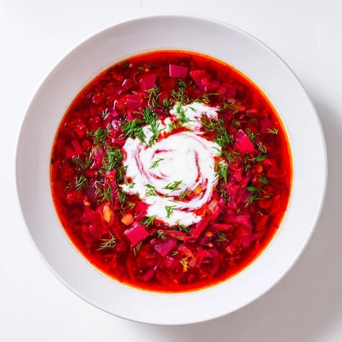 Vibrant Beetroot Borscht with a creamy coconut swirl, ready to be served hot in bowls.