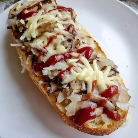 Pyszna zapiekanka z bagietki z pulchnymi pieczarkami i roztopionym serem, gotowa do spożycia.