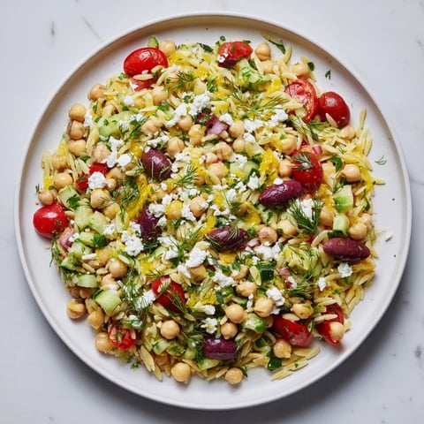 A colorful bowl of Greek Lemon-Orzo Bean Salad, bursting with fresh herbs and tomatoes.