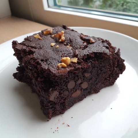 Fudgy baked black bean brownies, pictured with scattered chocolate chips, ready to enjoy after cooling.