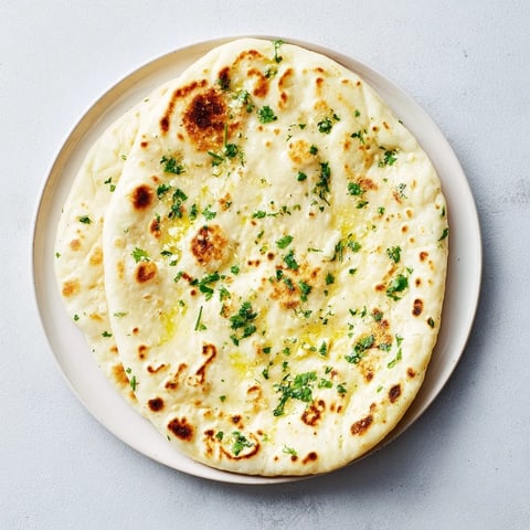 Homemade Garlic Naan Bread, golden and bubbly after being cooked in a hot skillet, ready to serve.