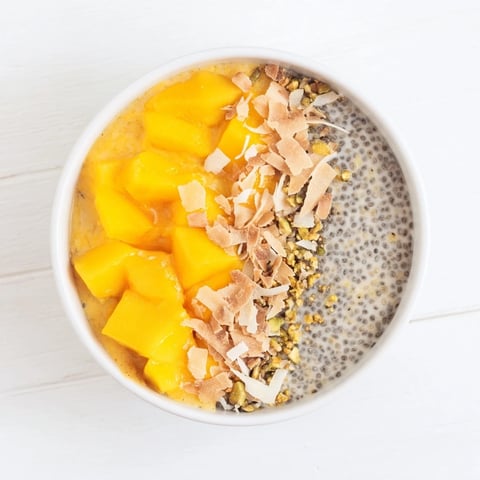 Creamy mango coconut chia pudding dessert, beautifully layered, garnished with fresh mango chunks.