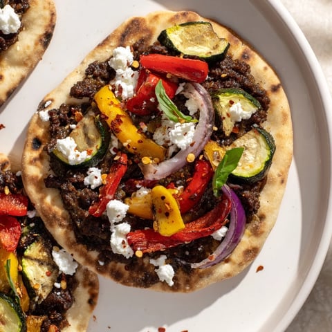 Naan bread pizza, ready to eat, with roasted veggies, feta, and olive tapenade.