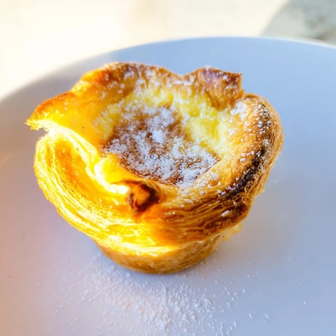 Golden, flaky Portuguese egg tarts with creamy custard filling, a perfect dessert.