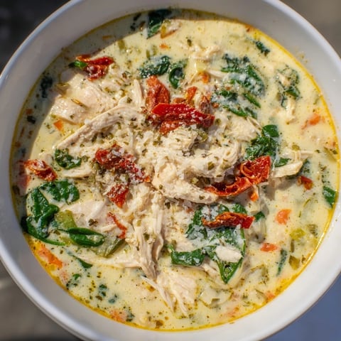 Creamy Tuscan Chicken Soup simmering in a pot with vibrant chopped spinach and sun-dried tomatoes.