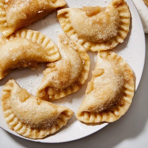 Złociste, domowe pierogi z jabłkami pieczone w piekarniku, idealne z sosem waniliowym.