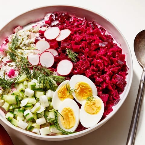 Creamy bowl of bright pink Chłodnik, a chilled beet soup garnished with dill and egg.