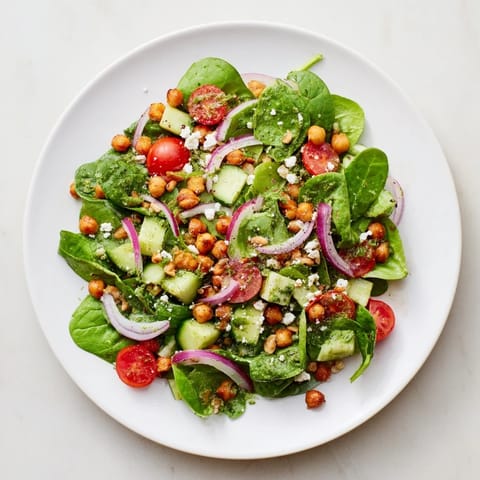 Enjoy the freshness of pesto chickpea and spinach salad, a Mediterranean delight with tomatoes.