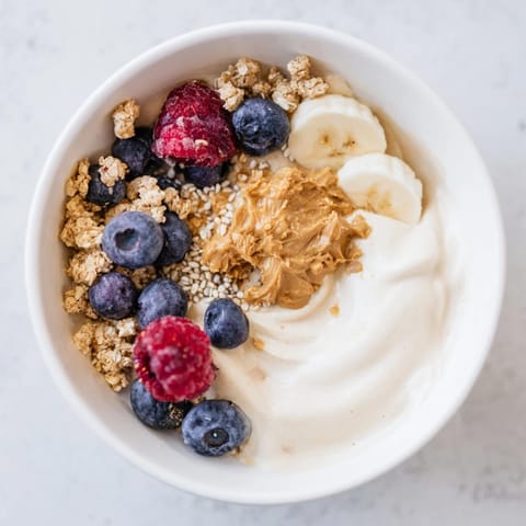 Pełna miska proteinowych lodów, z wiórkami banana i jagodami, to zdrowa alternatywa.