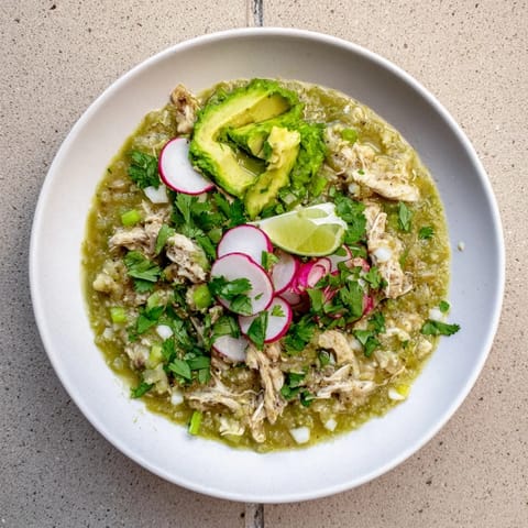 Savory Chicken Chili Verde simmered in a charred tomatillo-pepper sauce, garnished with radishes and lime wedges for a fresh Mexican-inspired meal.