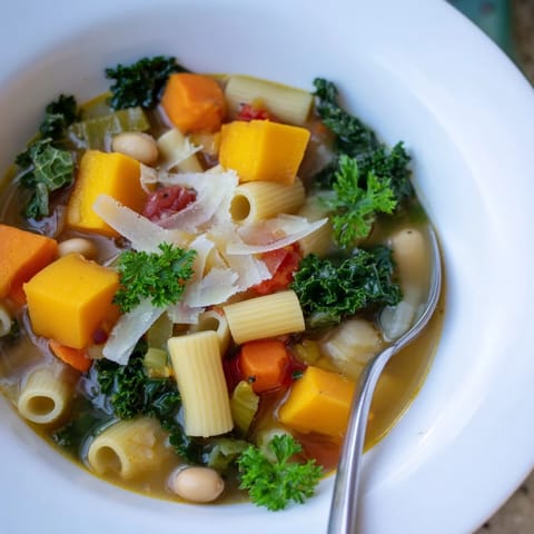 Rozgrzewająca zupa Winter Minestrone z kawałkami dyni, zieleniną i fasolą w misce, idealna na chłodny dzień.