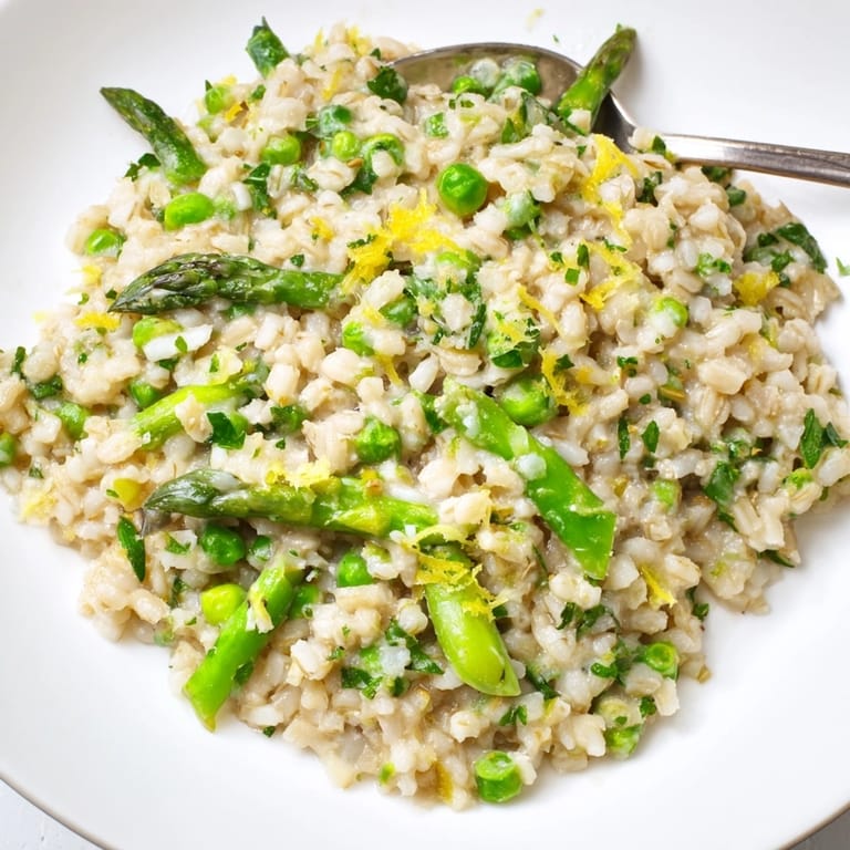 Apetyczne jęczmienne risotto ze szparagami i groszkiem, posypane serem, zachęcające do jedzenia.