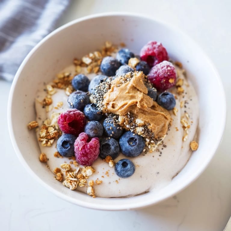 Świeże owoce i orzechy na szczycie miski proteinowych lodów kuszą swoim wyglądem i zapachem.