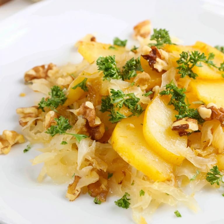 A bowl of warm apple and sauerkraut skillet salad, topped with crunchy walnuts and fresh parsley, perfect as a gut-healthy vegetarian side dish.
