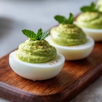 Trzy jajka z moussem ziemniaczanym i liśćmi szpinaku na podstawie.